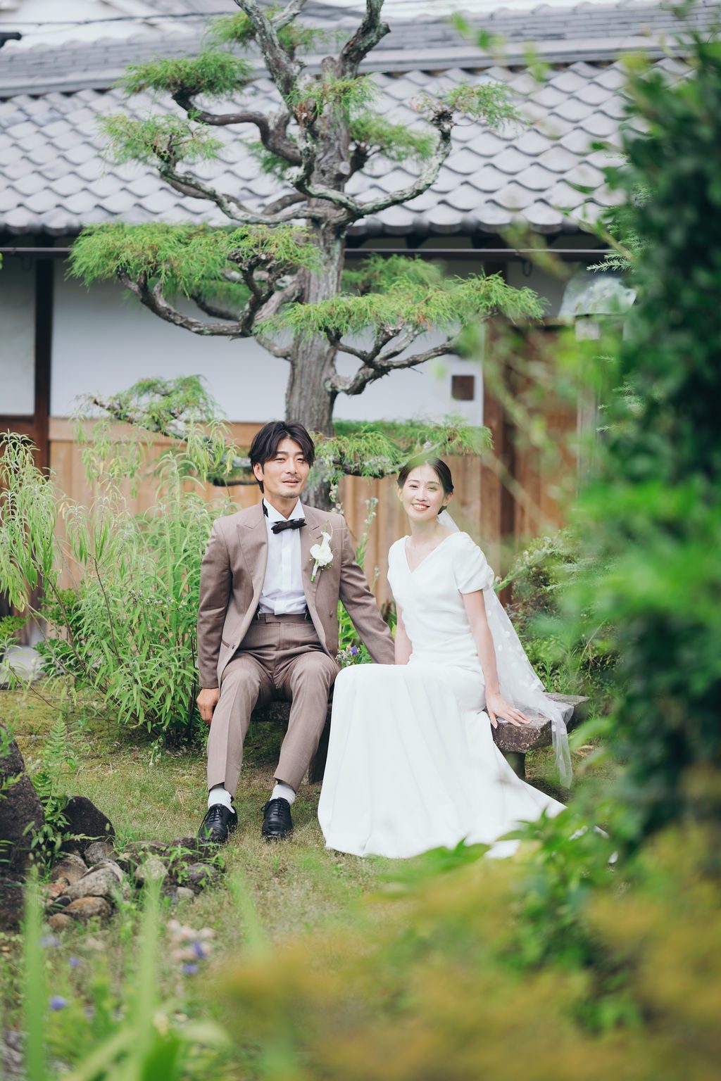 古民家の庭のベンチで寄り添い微笑む新郎新婦