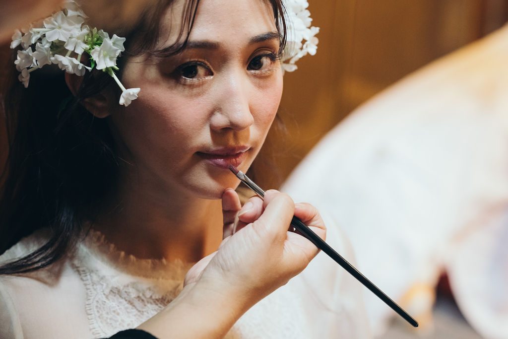 花を飾った髪に、丁寧にメイクを施される花嫁