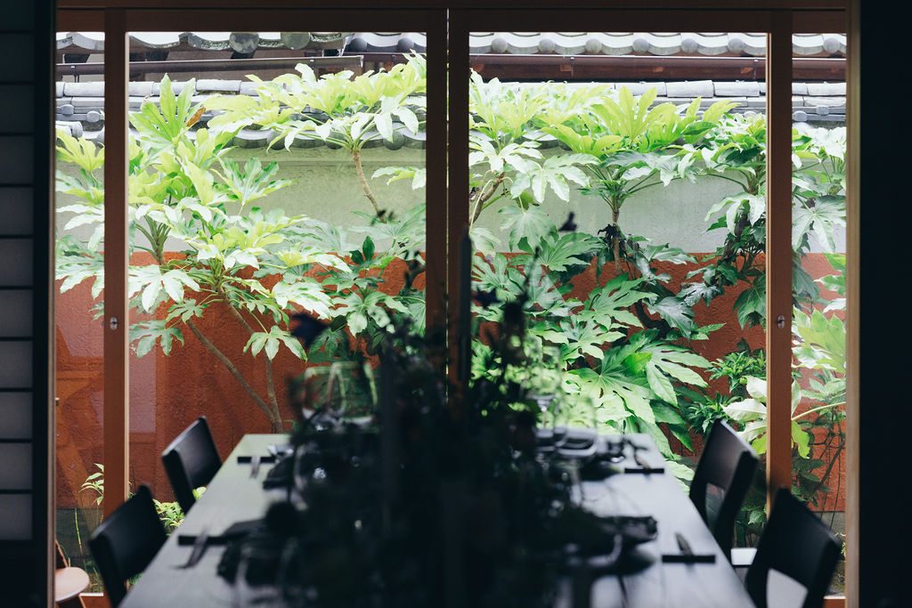古民家の食卓と、窓の外いっぱいに広がる手入れされた庭の緑